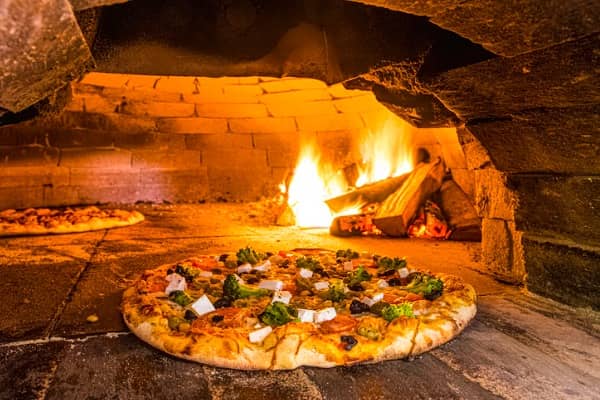 Kiln-dried hardwood heats three different pizzas in an oven