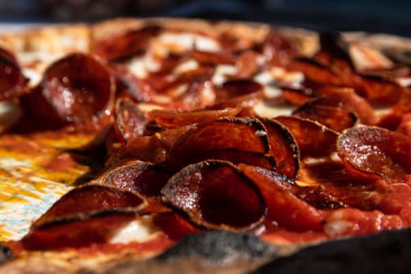 A wood-fired pizza covered in crispy pepperoni 